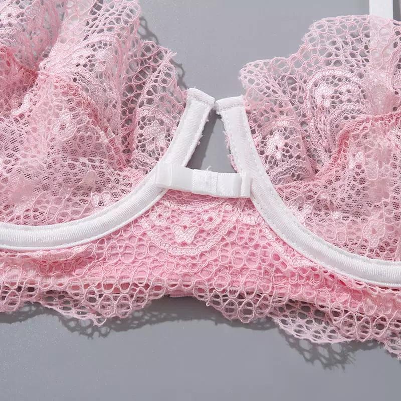 Detalhe do fecho e renda delicada de sutiã rosa claro com acabamento branco em elástico, textura floral em close.