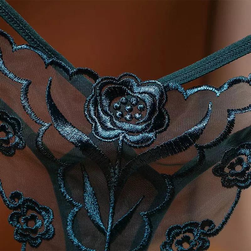 Detalhe de calcinha em renda verde escura, com bordado floral metálico sobre tule transparente.
