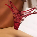 Calcinha fio dental vermelha com renda delicada, design transparente e detalhes florais elegantes.