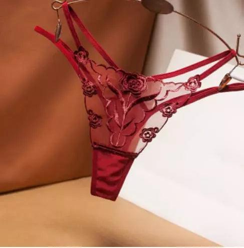Calcinha fio dental vermelha com renda delicada, design transparente e detalhes florais elegantes.